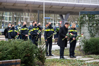 911077 Afbeelding van enkele agenten tijdens het leggen van bloemen bij de herdenking van de tramaanslag op 18 maart ...